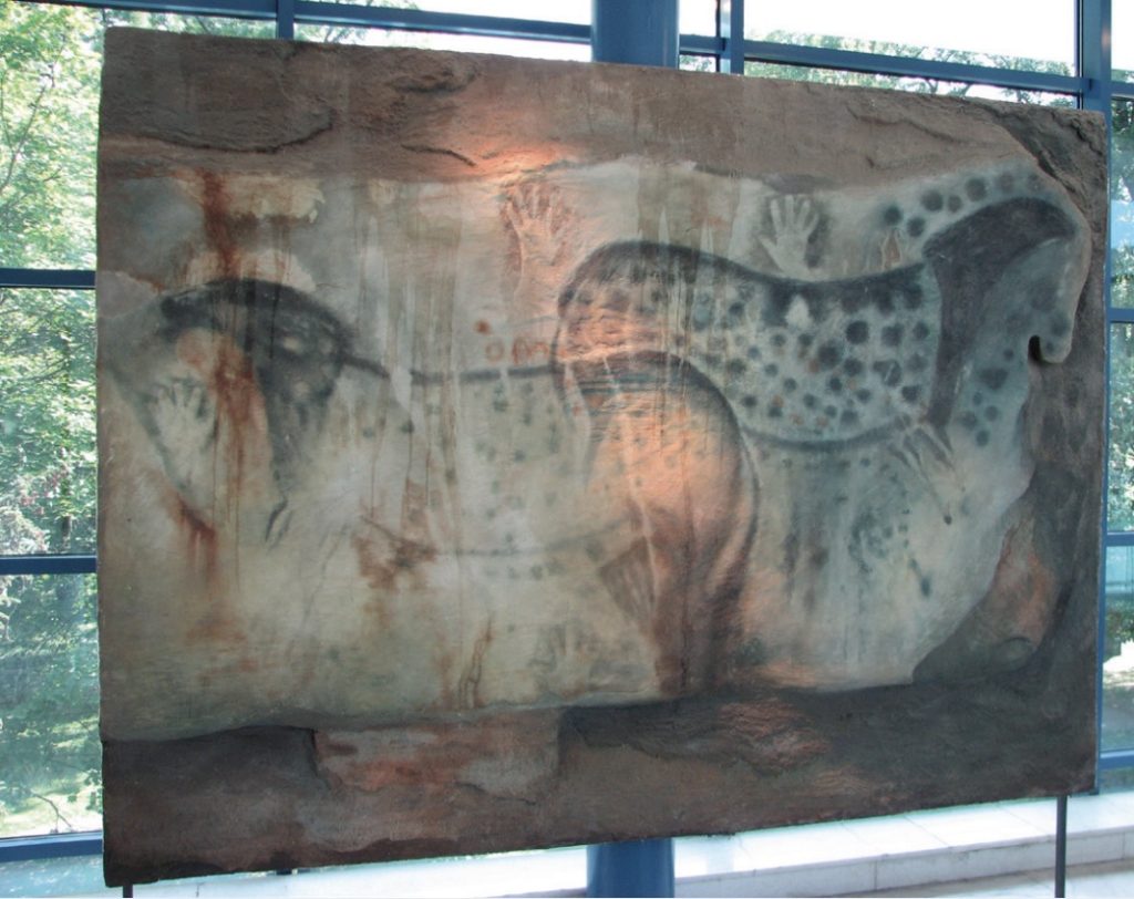 Photo of cave painting replica hung against bright windows