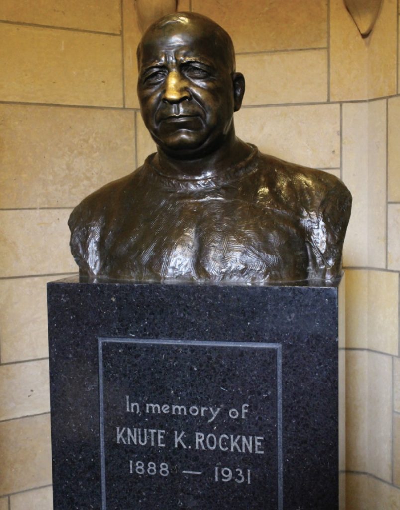 Photo of bronze bust of Knute Rockne with a bright gold nose.