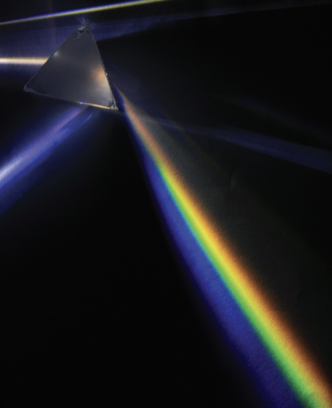 Image of light shining through pyramid prism throwing rainbows