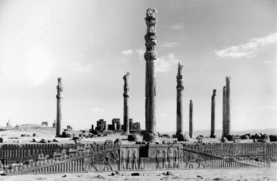 Photo of the remnant of a stone building, showing the remaining columns and a staircase leading to up to first floor