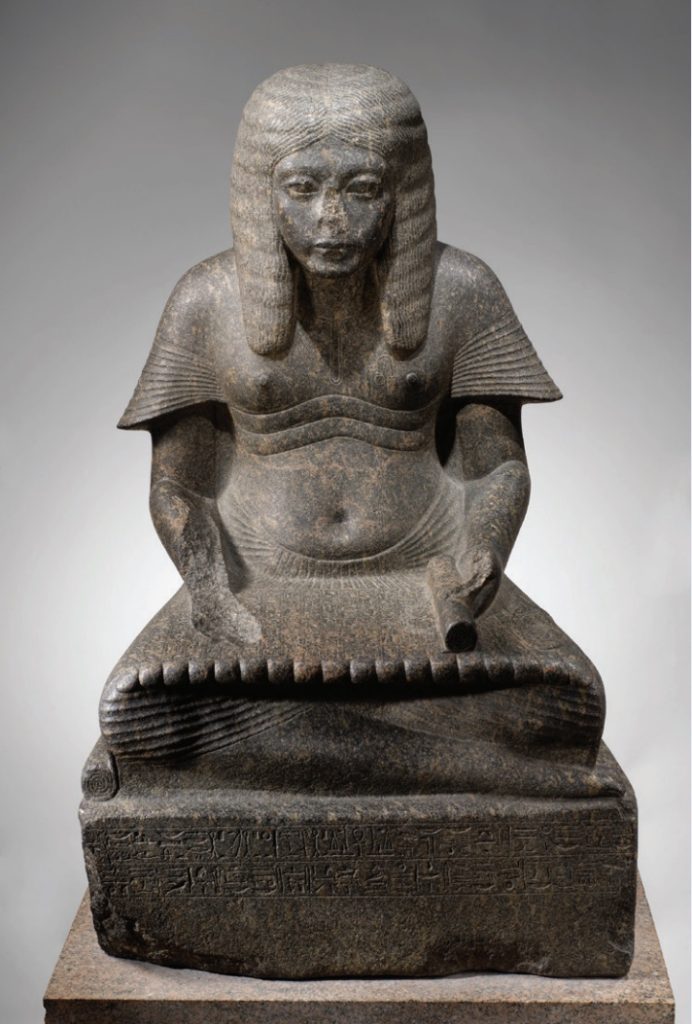 Photo of a sculpture of an ancient Egyptian scribe in traditional Egyption dress.