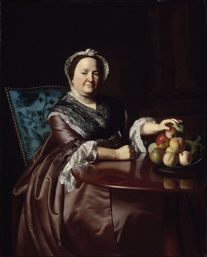 Painting of woman in 18th century dress and bonnet, sitting at table with hand on fruit in bowl.