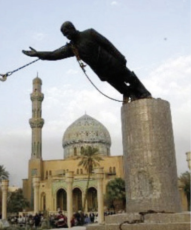 Photo of statue of Saddam Hussein being topped over using attached chain.