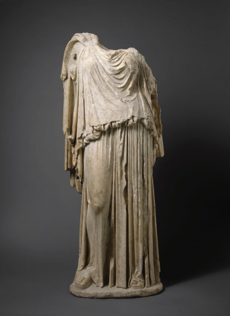 Photo of marble statue of headless woman in robe.