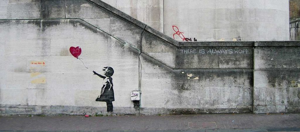 Photo of a painting on a wall of a little girl releasing a heart-shaped balloon.