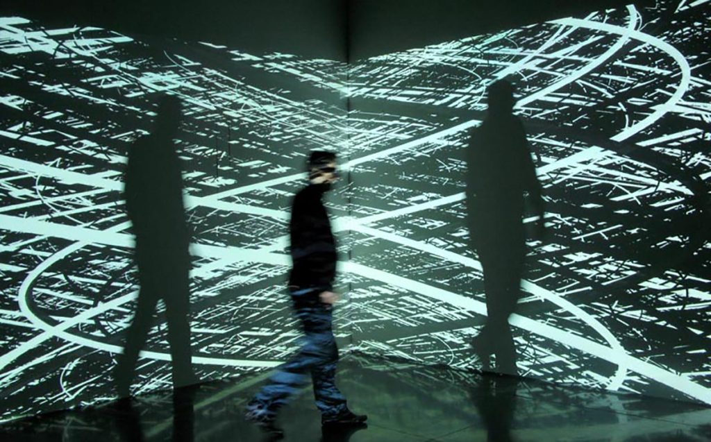 Image of Irrational Geometrics by Pascal Dombis. Shown is a man walking in front of the digital art installation.