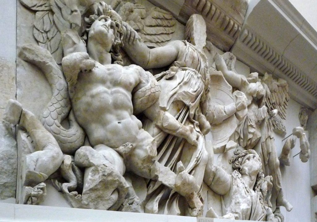 Image of the Great Altar of Pergamon, detail of the Great Frieze showing the Gigantomachy, the battle of the Olympians against the Giants. Athena shown in the center, defaced, pulling Alcyoneus by the hair pulling him out of the earth. To the right, Gaia (Alcyoneus' mother) shown with fear. Winged Nike shown behind Athena coming in to crown her.