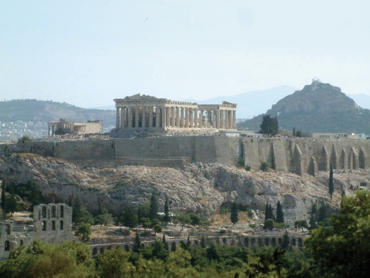 Photo of a crumbling temple (Acropolis) at top of hill with large columns around perimeter.