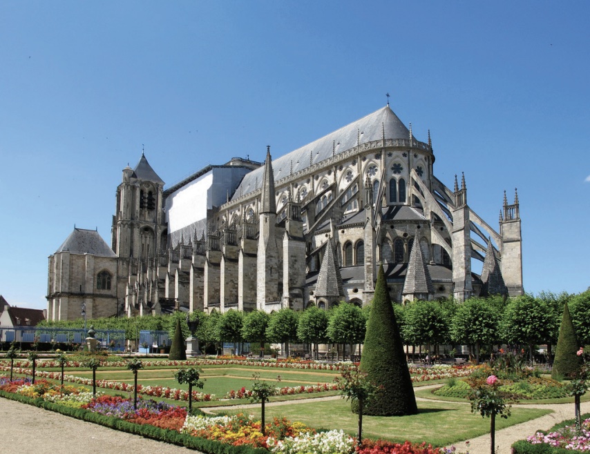 Photo of a large cathedral with flying buttresses along its entire perimeter and immaculate gardens in forefront.
