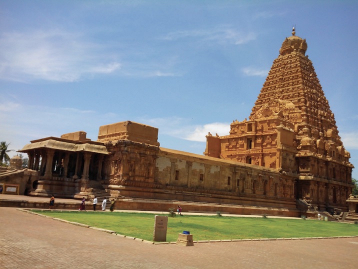 Photo of a tall, pyramid-shaped temple in orange-sandstone color with long low structure at entrance.