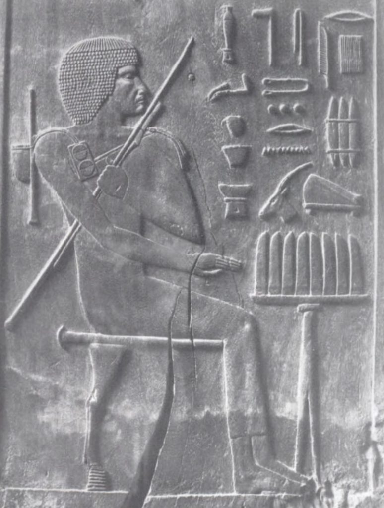 Image of carving of ancient Egyptian male holding and using tools.