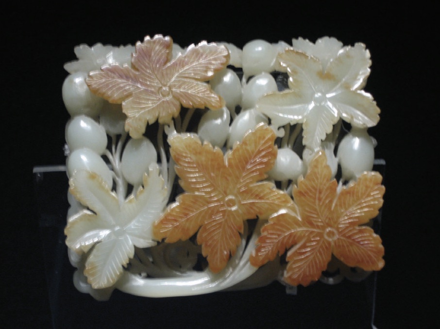 Photo of small off-white ornament with carved flowers made of jade.
