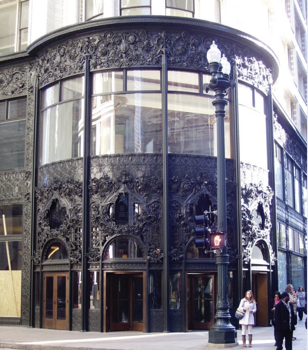 Photo of entrance of building on corner of street with dark and ornate metalwork.