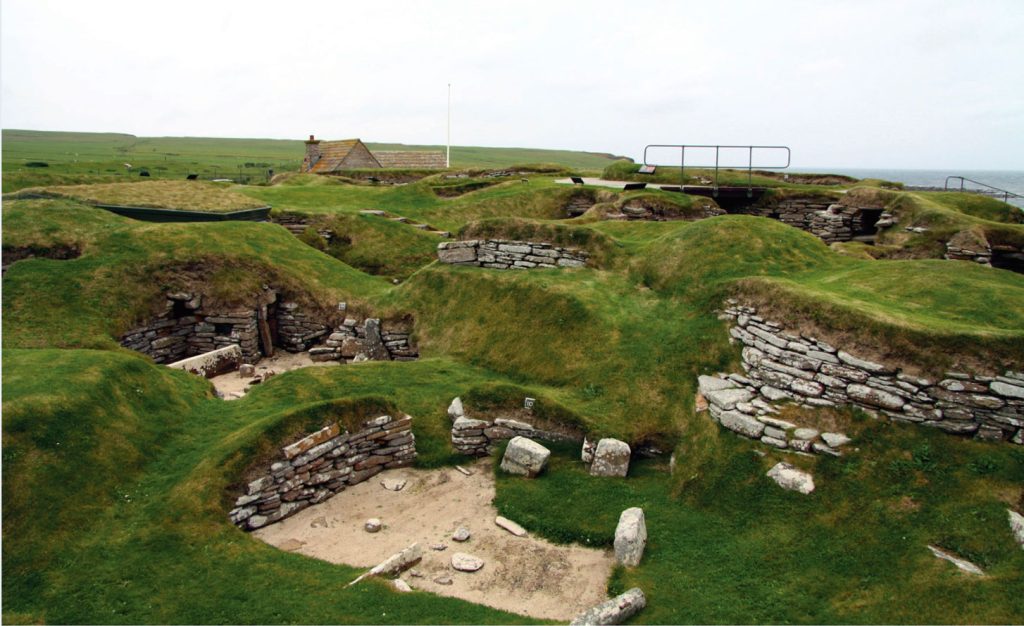 Photo of a settlement with stone walls and covered in green moss, built underground.