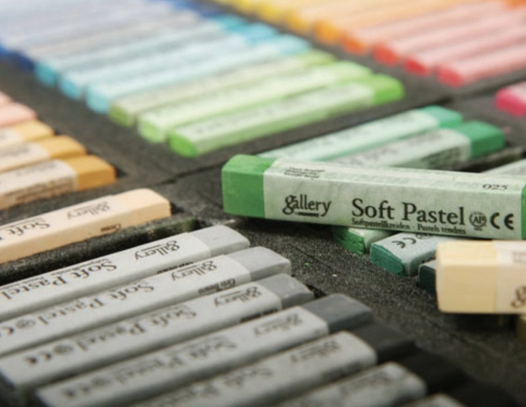 Photo of pastel crayons in multiple colors in a black tray.