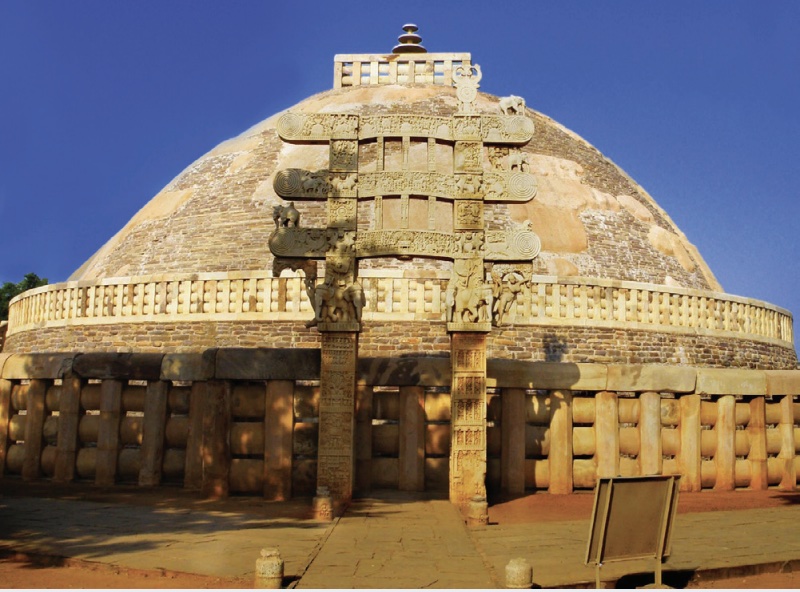 Photo of a stupa, a dome-like structure surrounded by a tall stone fence.