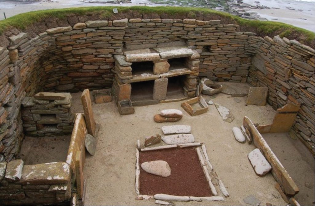 Photo of stone-walled structure with dirt walls and grass built up around perimeter.