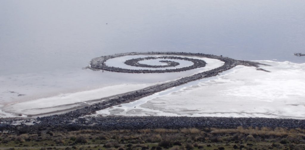 Photo of a spiral-shaped jetty jutting out in the ocean from the shore.