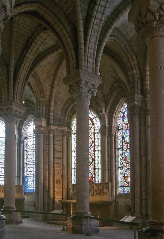 Photo of interior of St Denis Cathedral with colums, arches, and tall, colorful stained glass windows.