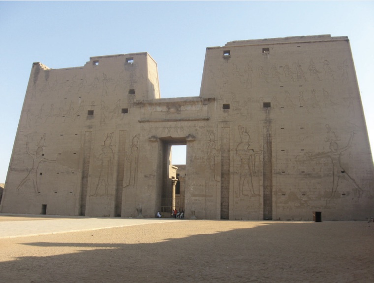 Photo of a temple with tall and wide outer walls forming facade.