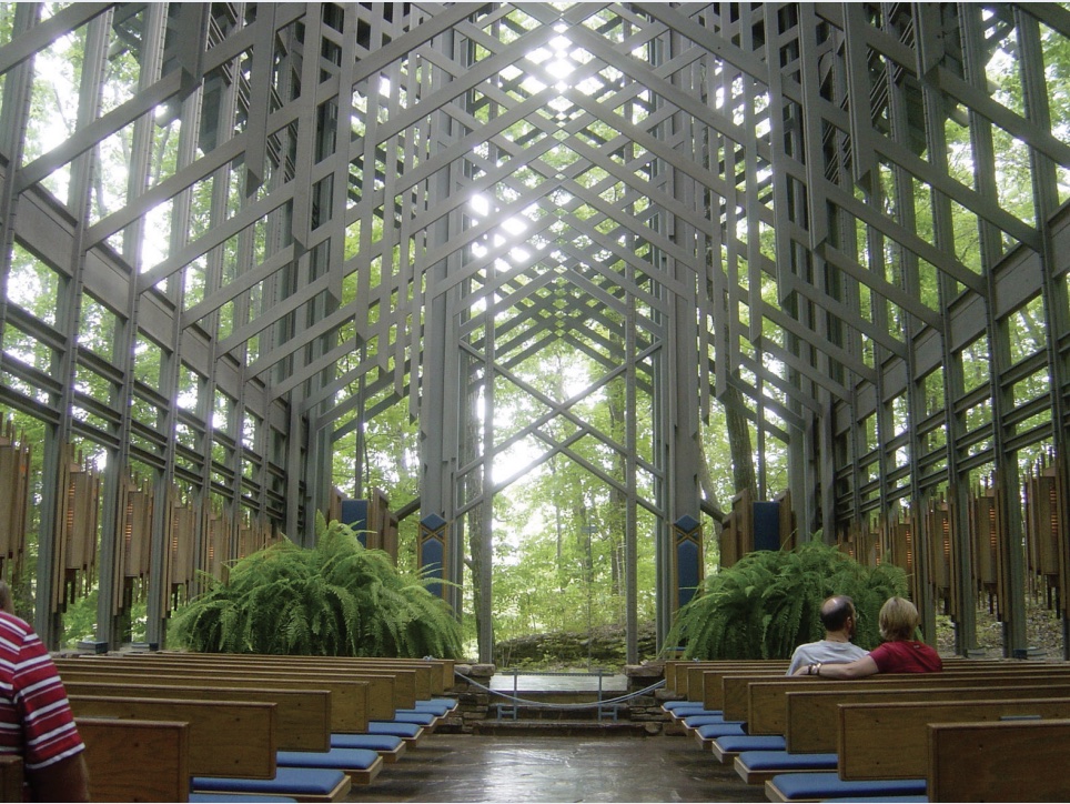 Photo of interior of Thorncrown Chapel showing diagonal beams, airy light, indoor plants, and pews.