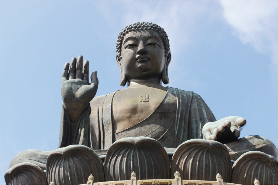 Photo of statue of a buddha with hand raised.