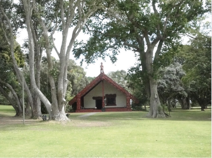 Photo of a small house with steeply slanted roof set among trees.