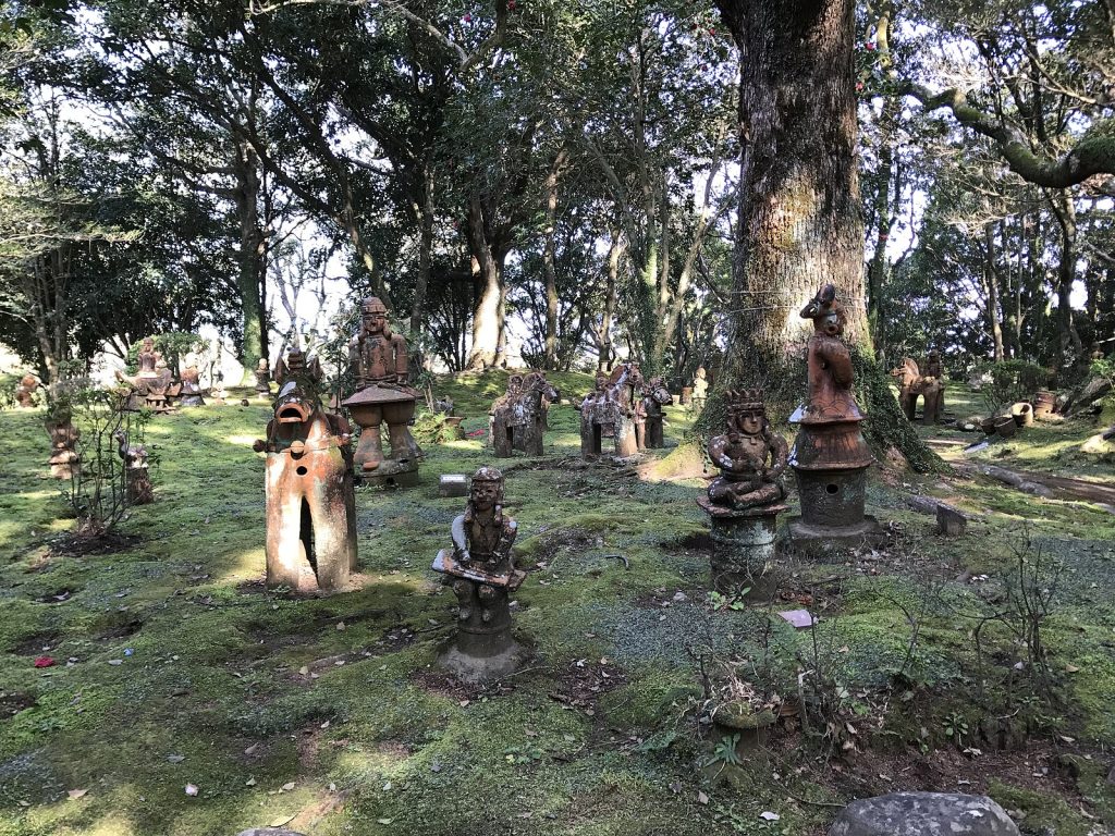 Photo small Haniwa statues in a green garden landscape among trees.