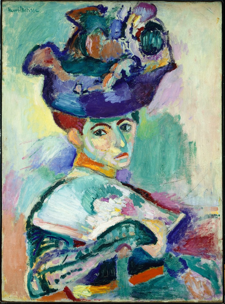 Image of Woman with a Hat by Henri Matisse. Shown is a woman with both colorful attire and hat. The woman is posed as looking over her shoulder. Oil on canvas painting.
