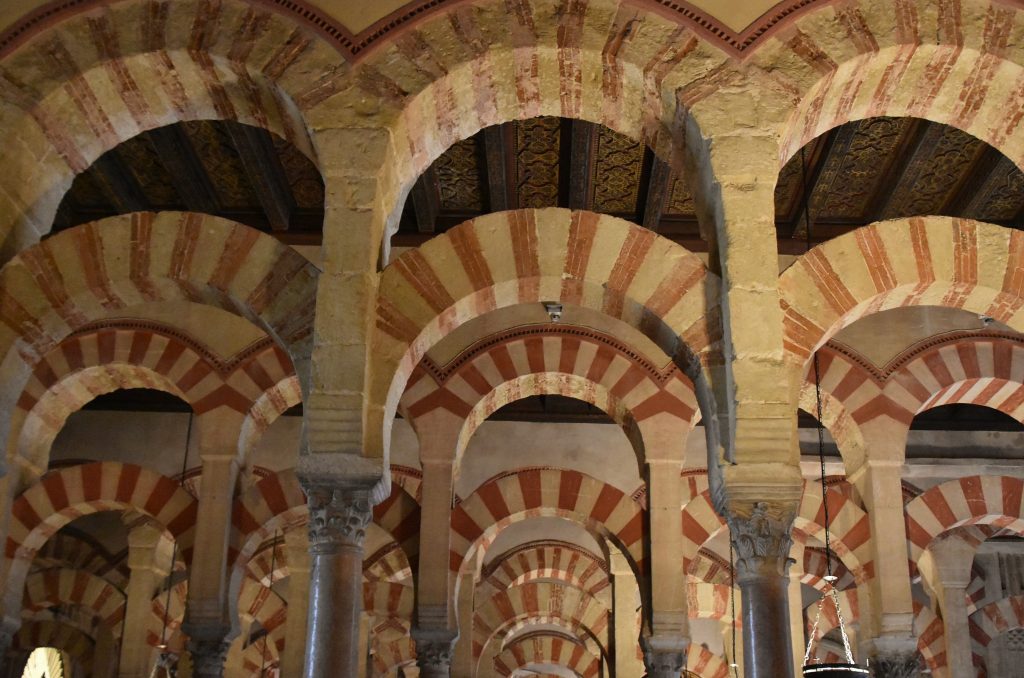 A great hall of arches and pillars. The tops if the arches are painted in red stripes.