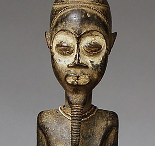 A close up photo of the diviner statue showinf the etched in designs on its head, nad white painted face.