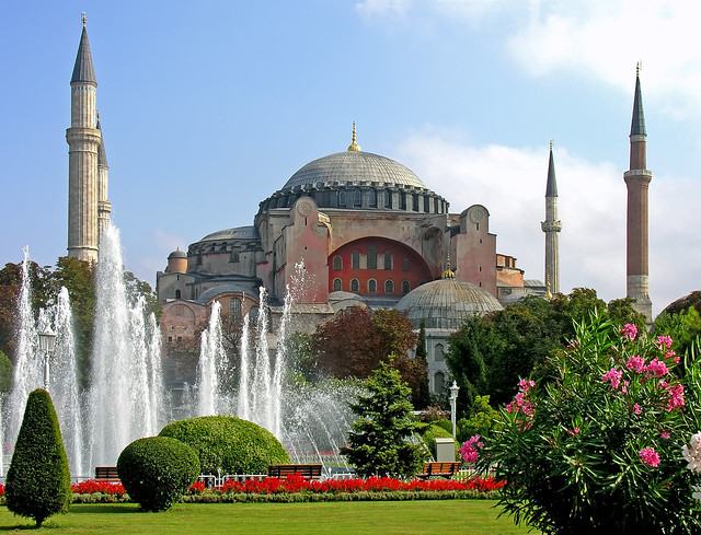 A photo of the exterior of Hagia Sophia, domed building with Minerets, with tourist walking ion front.