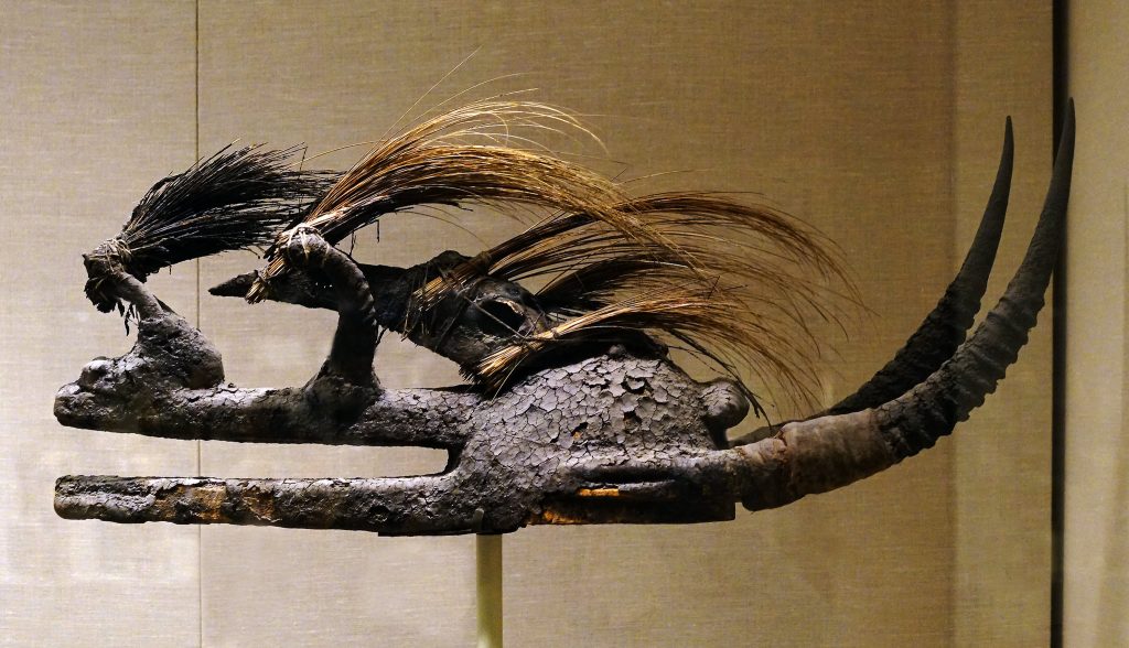 Helmet mask made of organic materials in a museum case.