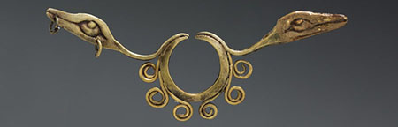 An elaborately carved metal nose ring with a serpent on each side.