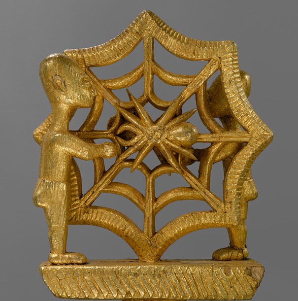 Close view image of Linguist Staff. Spider web shown with the spider in its center, two figures stand in front and behind the web each.