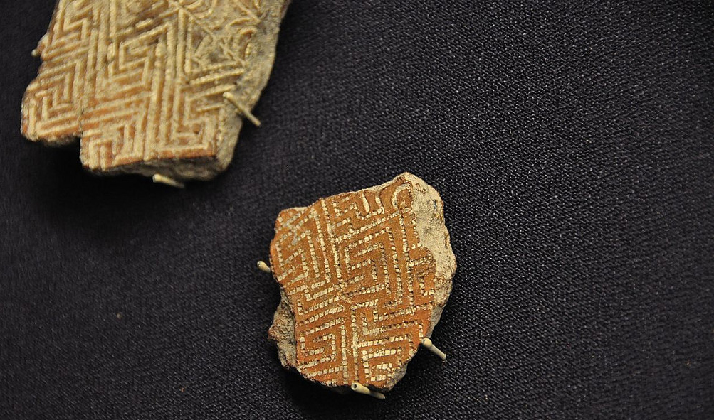 Small fragments of terra cotta pottery with white engraveds carved in geometric patterns.