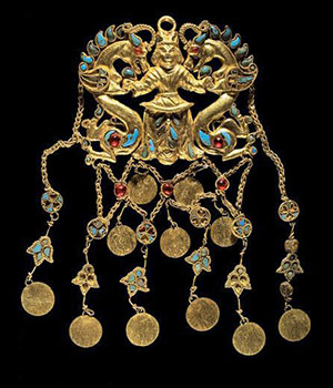 Image of an Inlaid gold pendant from Tillya Tepe. Figure shown in the center with dragons at each side.
