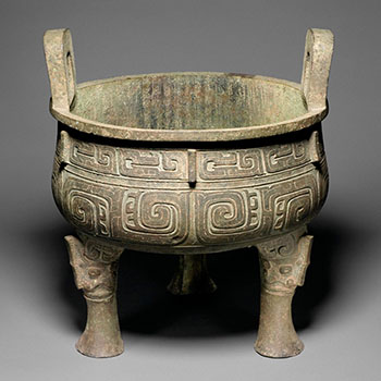 A pot with three legs, covered in geometric designs.