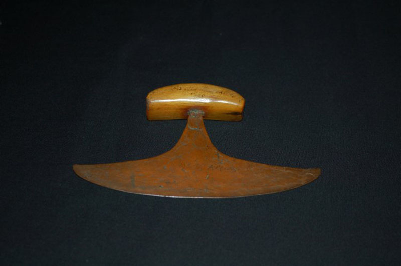 A crescent chaped knife with a wood handle set in the center of the copper blade.