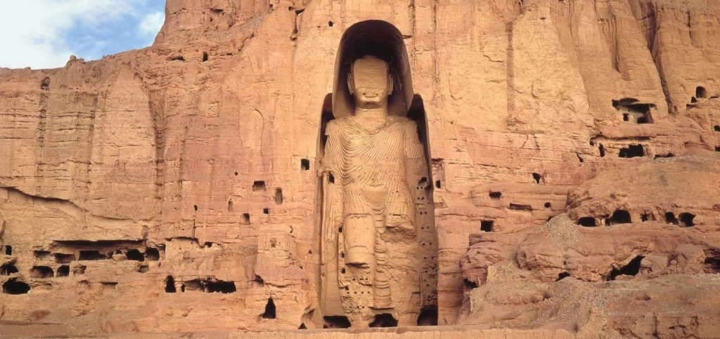 Image of the West Buddha at Bamiyan, Afghanistan. Large 175 foot stone Buddha in a niche on the side of a cliff. The Buddha is defaced and missing arms and legs.