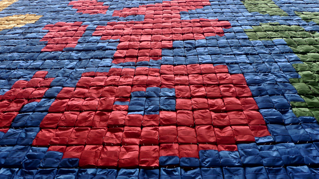 Close up of red, yellow, blue, and green backpacks arranged in Chinese letters.