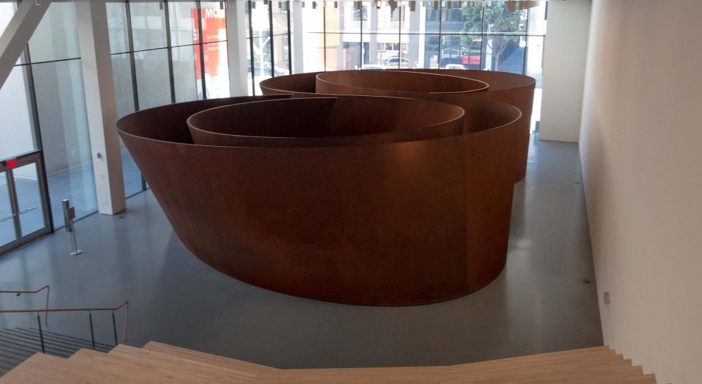 Steel sculptures in a museum. A pair of two concentric ellipses in an S-Shape made of rusted steel, and large enough to create a walking path through it.