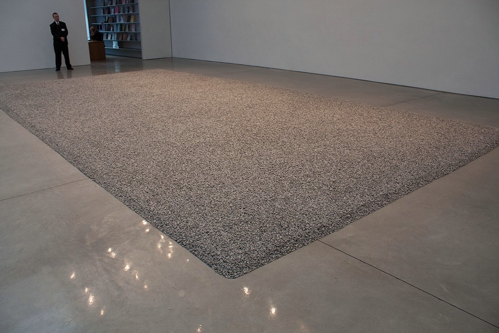 A floor of a room in a museum covered in a carpet of porcelain sunflower seeds.