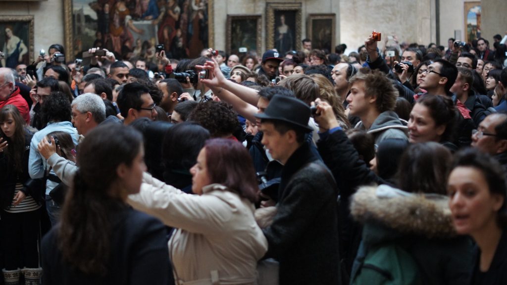 A crowd of people, arms extended holding different types of cameras, taking pictures.