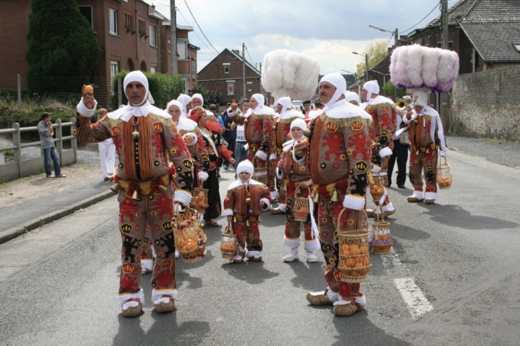 Photo of masked and costumed people parading down the street in neighborhood.