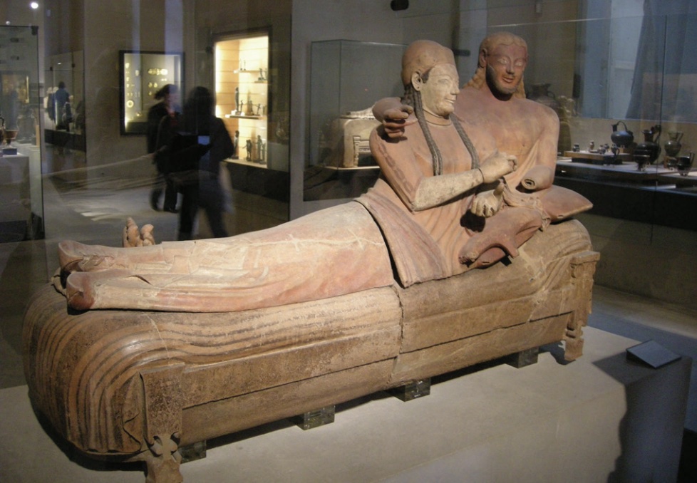 Photo of statue showing man and woman side by side lounging on bed.
