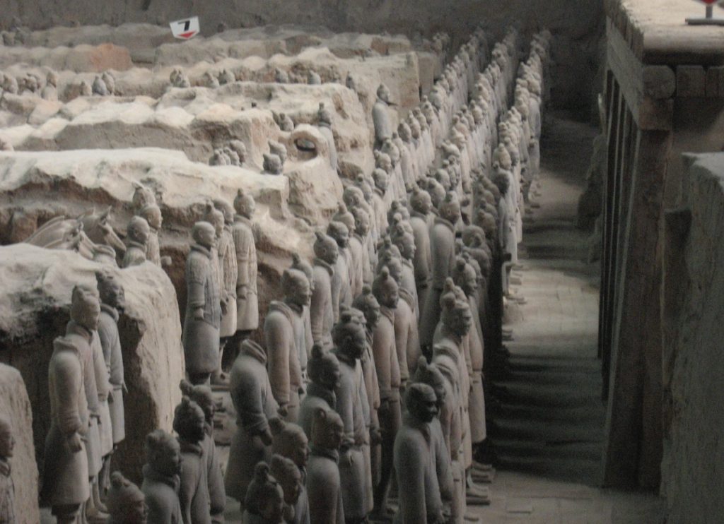 Photo of hundreds of statues of soldiers lined up in a row and standing guard.
