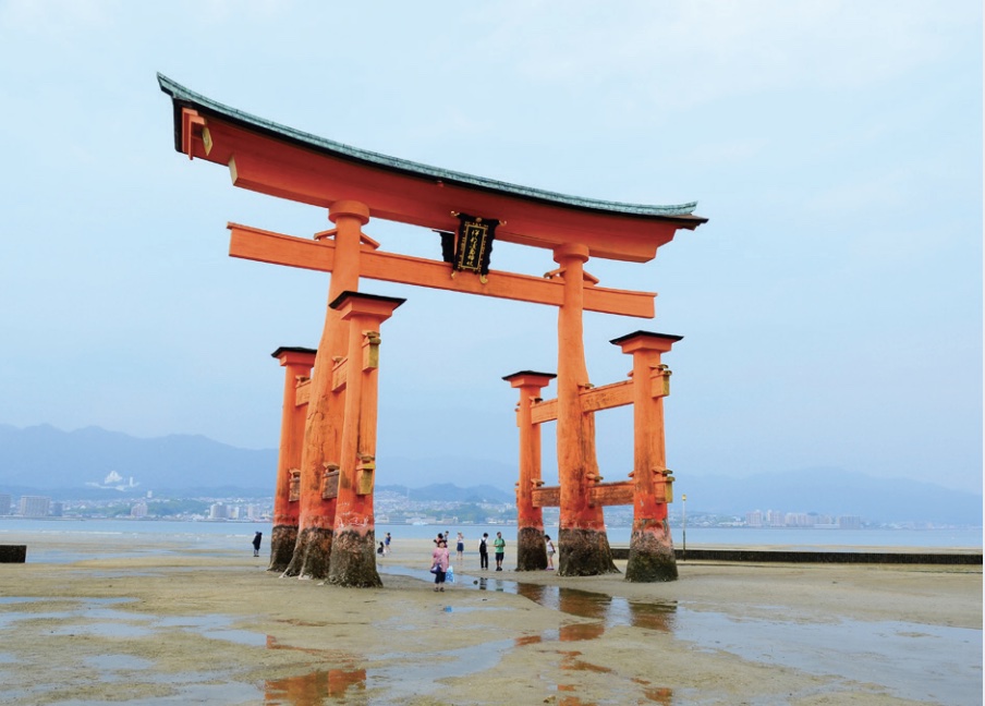 Photo of a gate-like structure constructed of bright orange columns set at sea, photo taken at low tide.