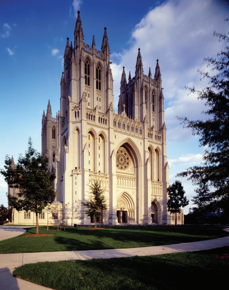 Photo of a large white cathedral with grassy lawn and trees.