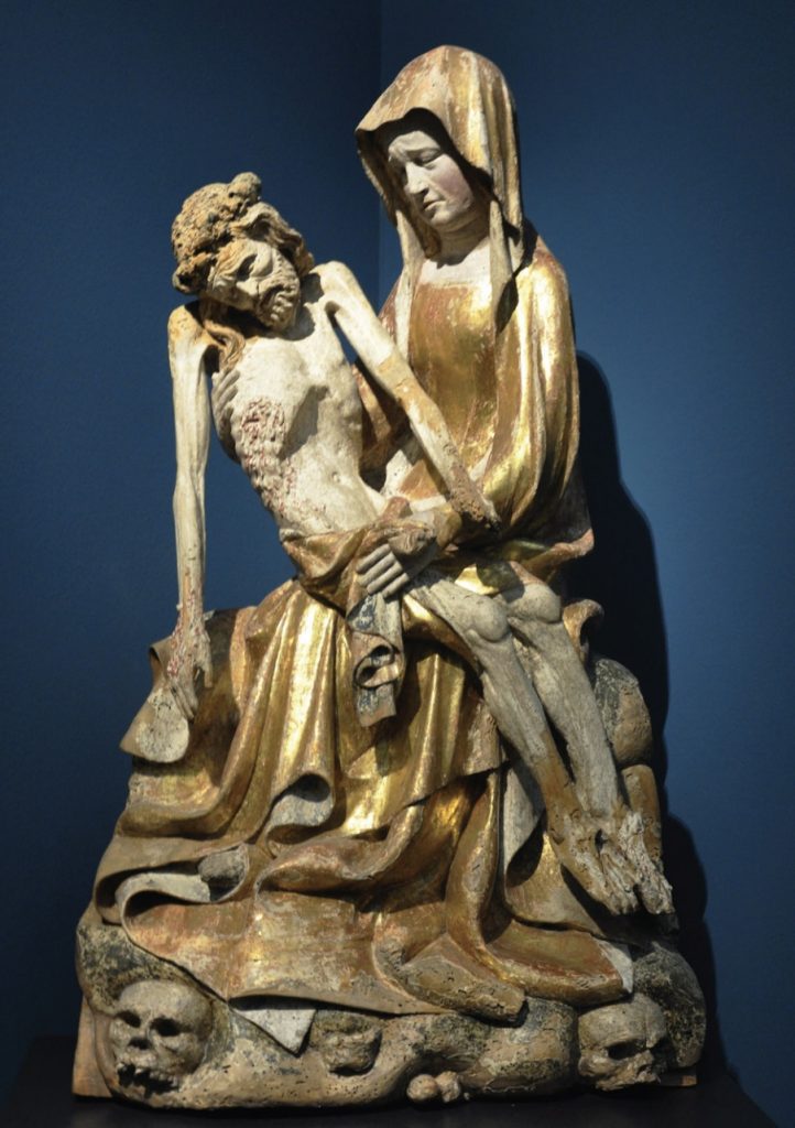 Photo of sculpture depicting a woman (Madonna) holding crucified Jesus in her arms.